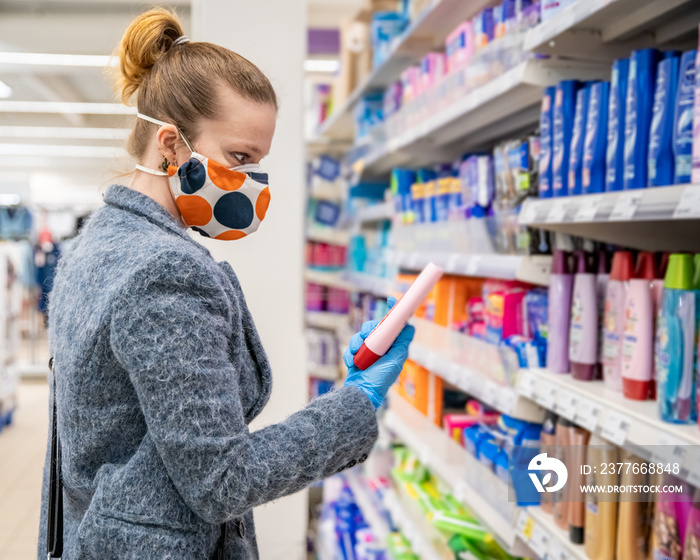 woman buying cosmetics in a shopping center with a health mask on her face during a coronavirus epidemic