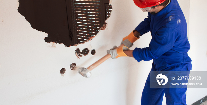 young worker with a red protection helmet and wearing a blue boiler suit. demolition concept