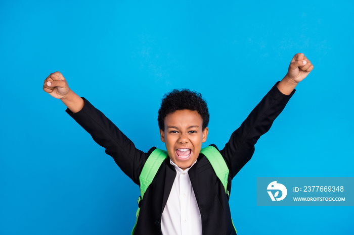 Photo of cheerful young happy positive boy raise fists winner good mood school isolated on blue color background