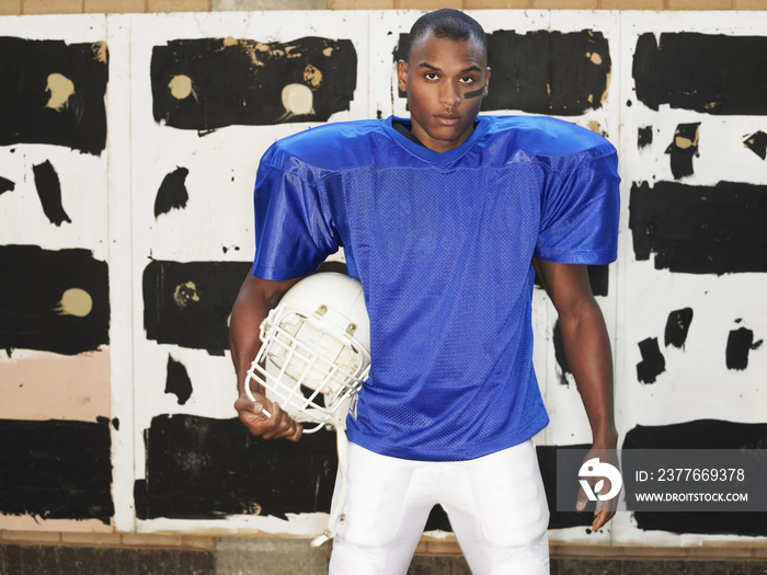 Portrait of an American football player holding helmet