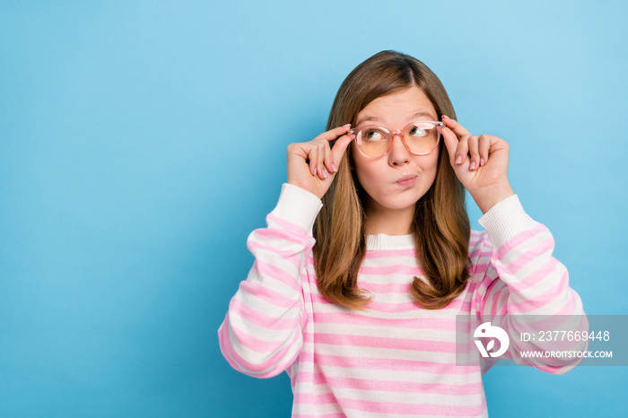 Photo of minded person arms touch eyeglasses look interested empty space isolated on blue color background