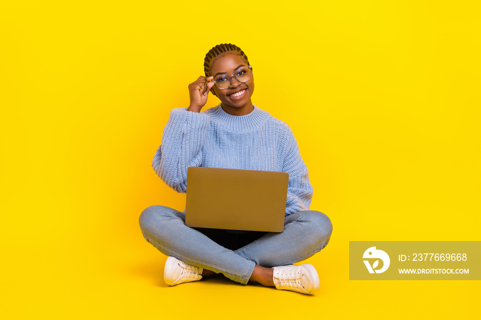 Full size photo of young lady wear blue sweater spending free time hold laptop programming showing new special eye glasses isolated on yellow color background