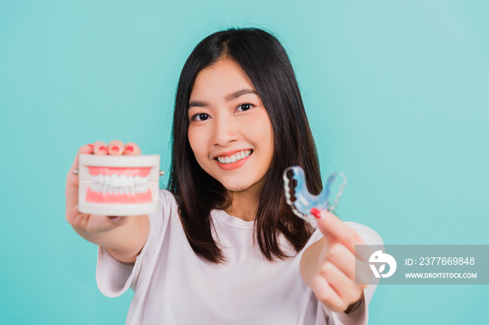 Portrait young Asian beautiful woman smiling holding silicone orthodontic retainers for teeth retaining tools after removable braces, Female hold model teeth before, Orthodontics dental healthy care