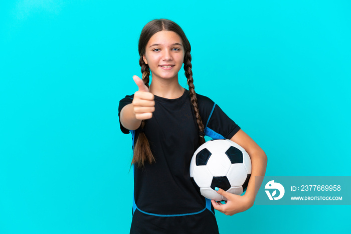 Little caucasian girl isolated on blue background with soccer ball and with thumb up