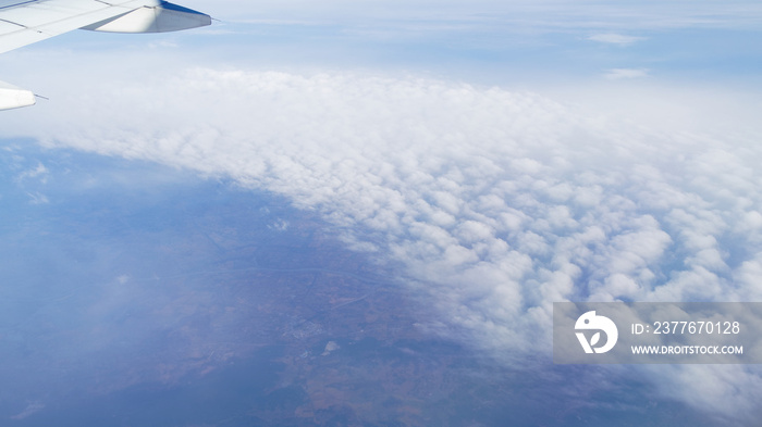 Wing of an airplane flying above the small town in Southwest China. The view from an airplane window. Travel concept.