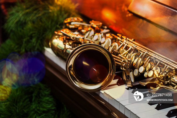 close up of alto saxophone  on the Piano Keys with Christmas tree and decoration light, in the night of Christmas season, Christmas background