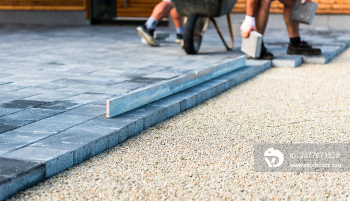 Laying gray concrete paving slabs in house courtyard driveway patio.