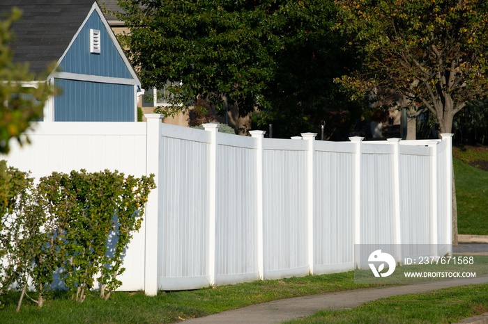 A new white vinyl fence by a grass area with trees behind it green property modern