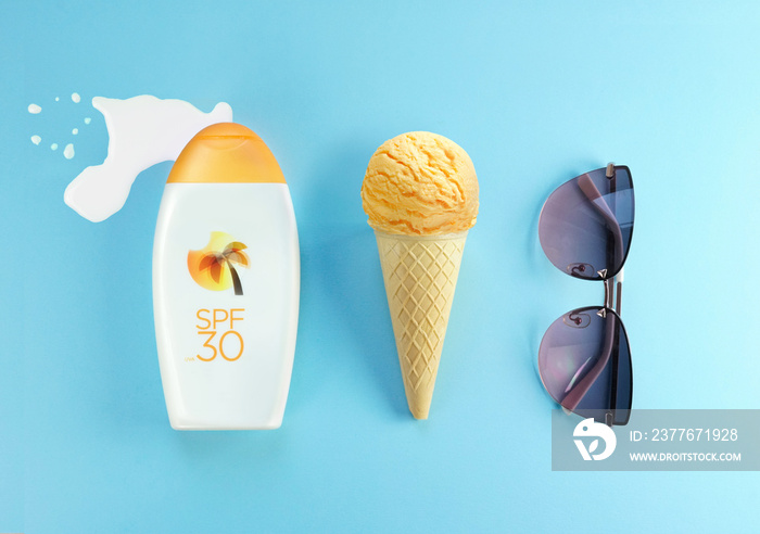 Creative layout concept for summer holidays. A set of sunglasses, orange ice cream cone and bottles of lotion against sunburn on blue background.