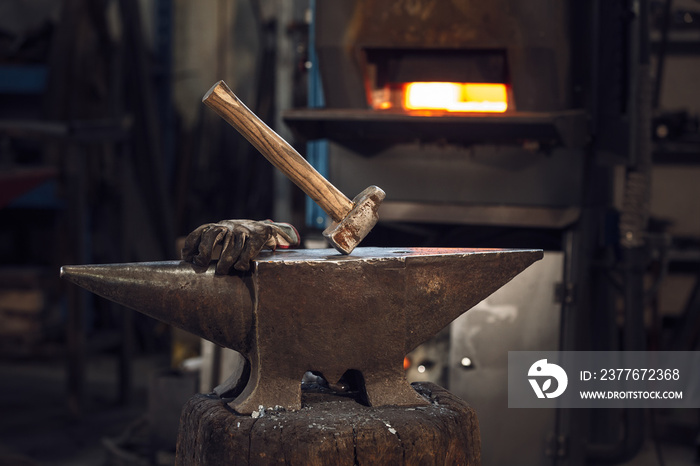 Mallet and gloves on an anvil in front of a furnace