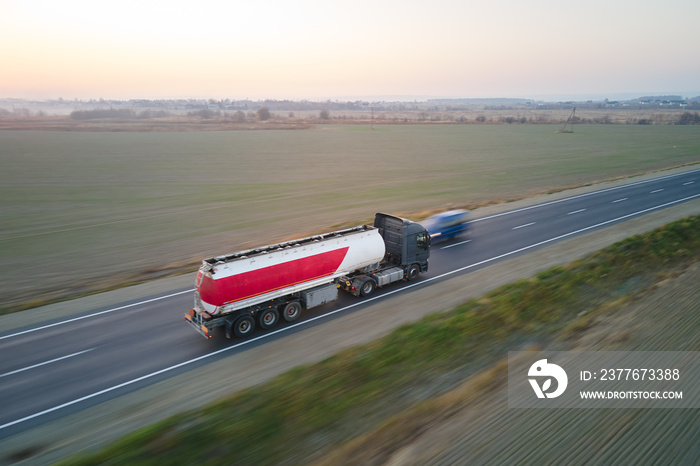 Aerial view of blurred fast moving fuel cargo truck driving on highway hauling goods. Delivery transportation and logistics concept