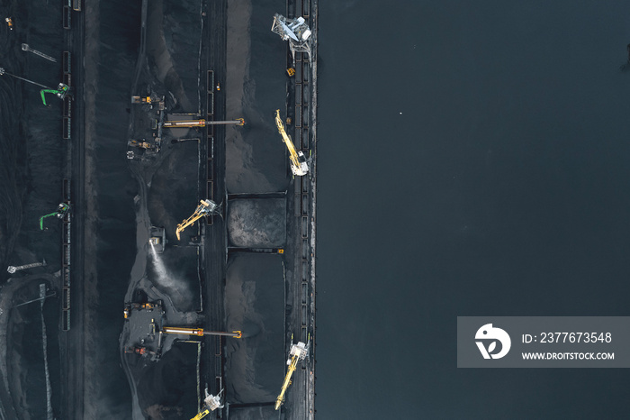 Work of cranes in cargo port, loading black coal on ship for export. Aerial top view