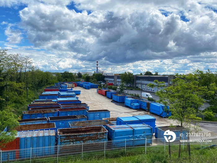 Empty truck containers and trailers ready to collect garbage and junk in an industrial waste management plant parking lot