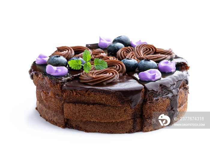 Sliced chocolate cake with buttercream decorated with berries isolated on white