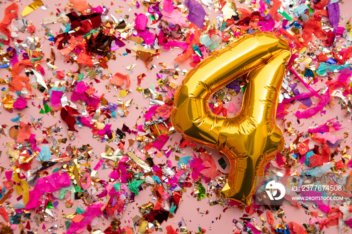 Number 4 gold birthday celebration balloon on a confetti glitter background