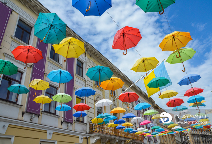 Street decoration, lots of colorful umbrellas in the air over old building and sky, Lviv, Ukraine