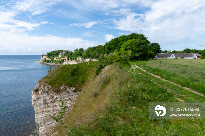 jagged white cliffs on the ocean coast with a church on the cliffside and farm fields