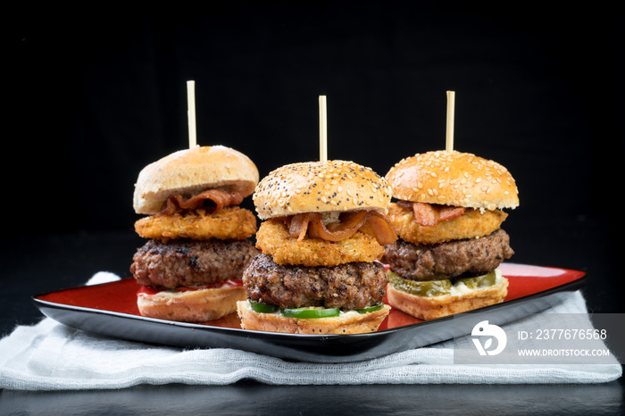 Small beef sliders grilled burgers onion rings little buns bacon served as appetisers for sharing