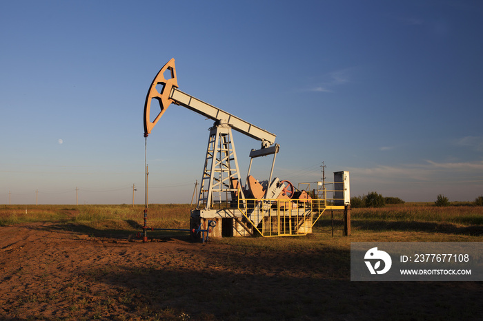 The oil pump, industrial equipment. Oil rocking at sunset in Russia, Republic of Bashkortostan