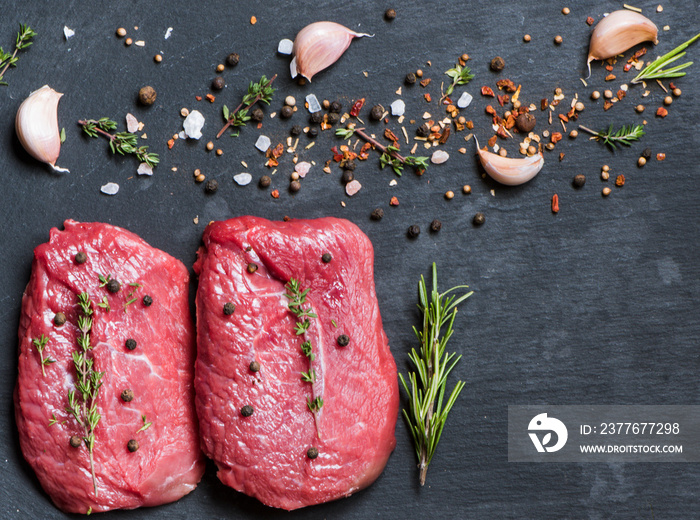 Two beef steaks with spices on a black background. Flat lay on gastronomic background