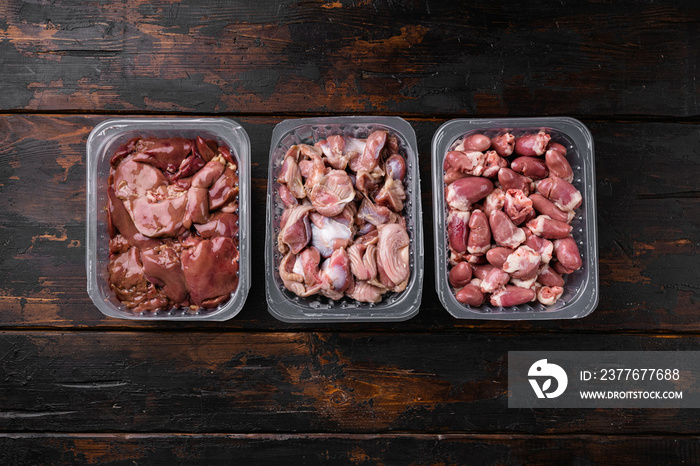 Raw uncooked Bird chicken giblets gizzards, stomachs, liver, offal, hearts, on old dark  wooden table background, top view flat lay, with copy space for text