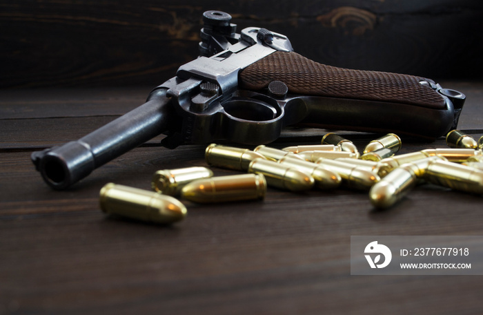 Historic Luger P08 Parabellum handgun, old soviet TT handgun and shiny 9 mm bullets on wooden vintage background