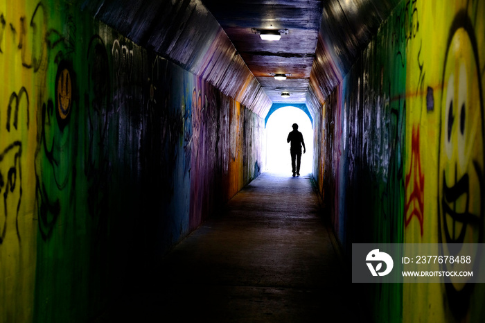 Man Walking Through Graffiti Tunnel Towards the LIght