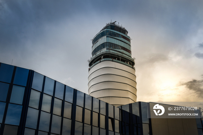 Airport control tower at Vienna in a cloudy evening. Flights management air control building and passenger terminal with clouds in the sky. Modern buildings. Architecture, business, travel concept.