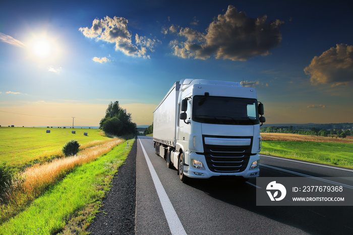 White truck driving through autumn landscape at sunset