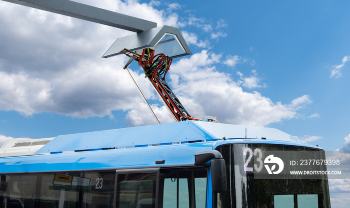 Electric bus at a stop is charged by pantograph