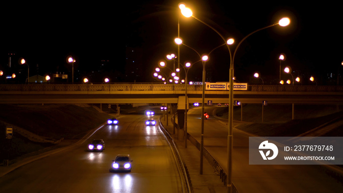 Beautiful scene of the street at night with many cars, night traffic. Stock footage. Late evening road under the street lamps full of vehicles driving into different directions.