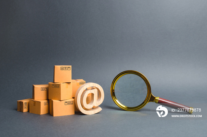 Pile of boxes with email symbol AT and a magnifying glass. Concept search for goods and services. Search for customers for sale, sales and retail. Tracking parcels via the Internet. Quality control