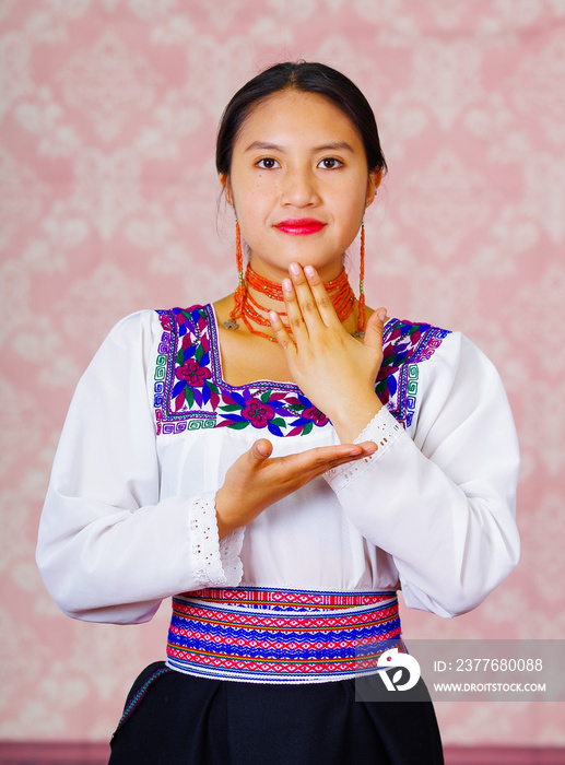 Young woman wearing traditional andean dress, facing camera doing sign language word for thank you