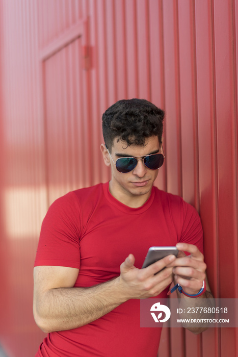 Young man in red sending text message by phone