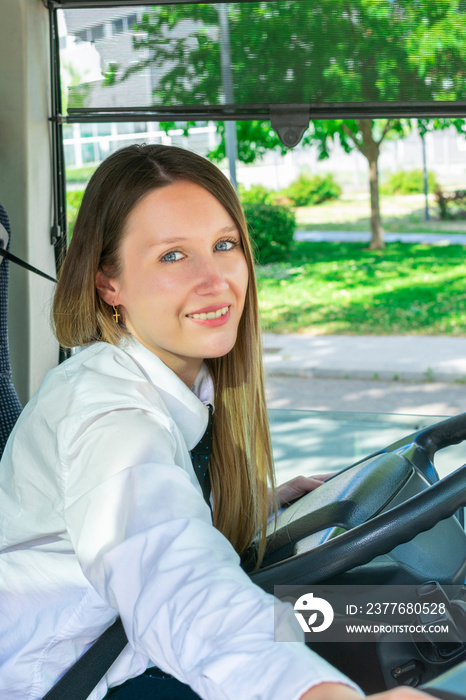 Pretty young bus driver smiles at the passenger as she collects the fare.