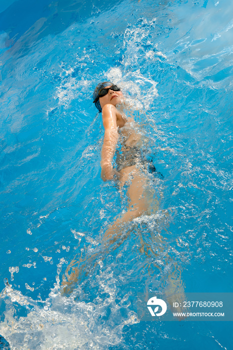 Boy swimming in indoor pool having fun during swim class