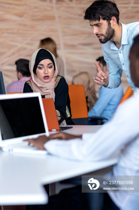 diverse college students using laptop and talking, learning exchanging ideas