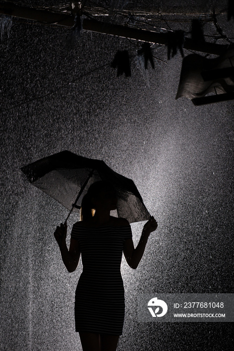 silhouette of the figure of a young girl with an umbrella in the rain, a young woman profile