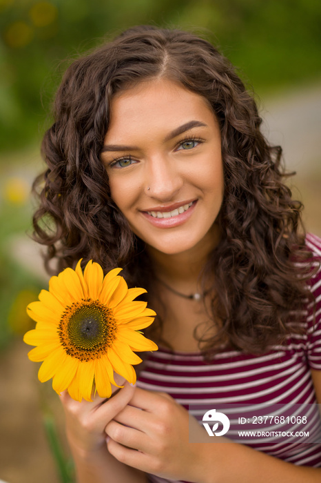 Happy teenage high school senior girl in sunflower field