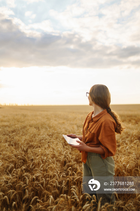 Young Female farmer with tablet in the field. Agriculture, gardening, business or ecology concept. Growth dynamics.