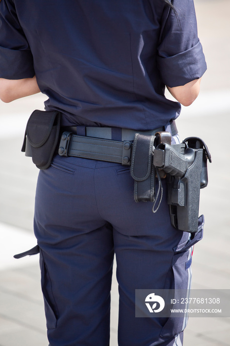 Armed Austrian Poliewoman from behind showing her navy blue uniform and pistol