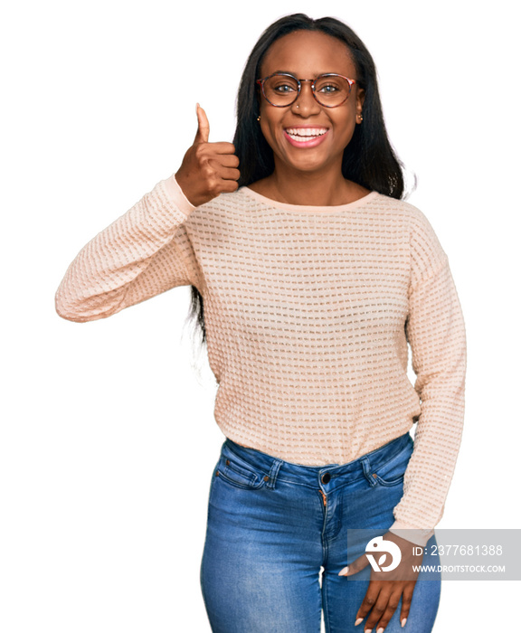 Young black woman wearing casual clothes and glasses smiling happy and positive, thumb up doing excellent and approval sign