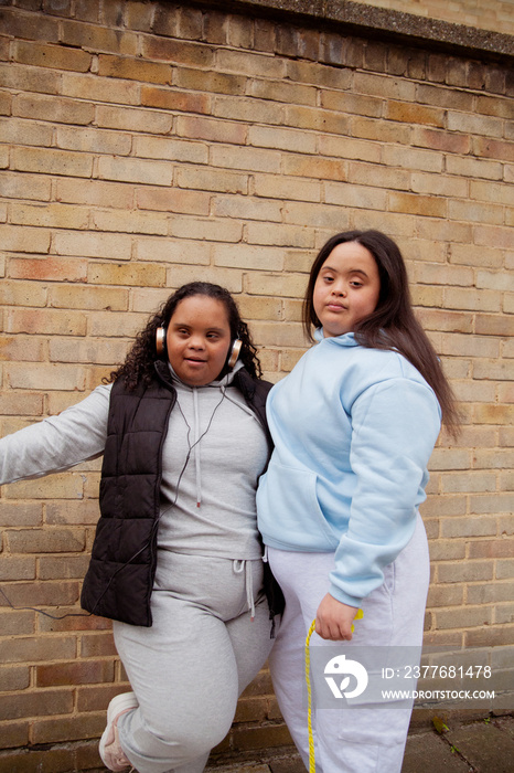 Two plus-sized women with Down Syndrome in workout clothes posing