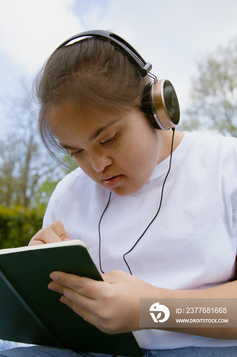 Young mid-sized woman with Down Syndrome listening to music in the park