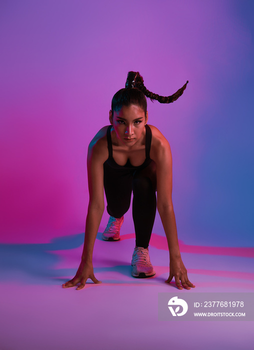Athlete asian sportswoman running as part of fat burning workout in fitness studio neon background. Woman exercising with cardio at the gym.