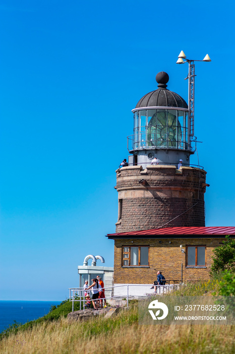 Kullaberg fyr, old lighthouse on the cliffs of Kullaberg naturreservat on the Swedish west coast. Lighthouse on the rocks viewing out into the baltic sea. Warm summer, high cliffs, deap ocean. Trees