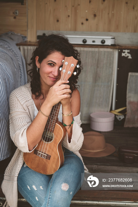 Girl sitting in her camper van with a ukulele in hand