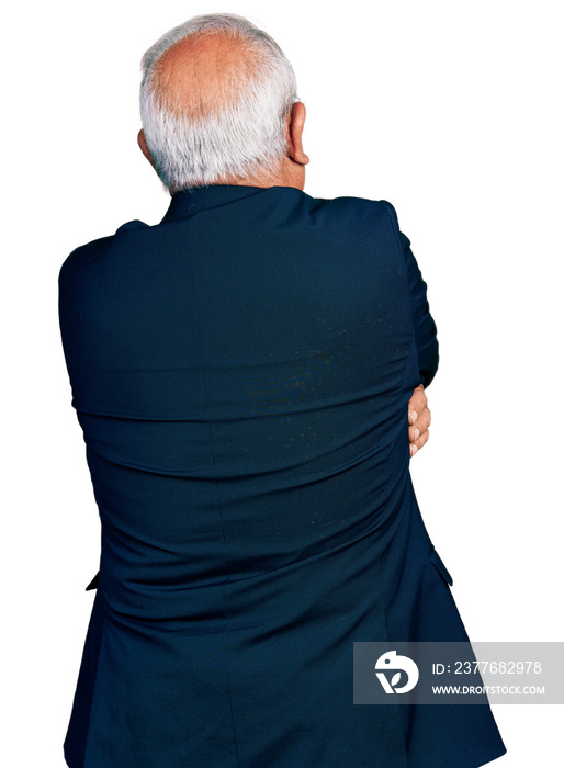 Senior man with grey hair wearing business suit and glasses hugging oneself happy and positive from backwards. self love and self care