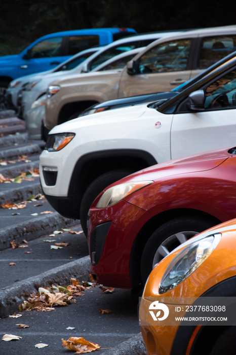 A row of cars with different colors and models lined up at a parking lot.