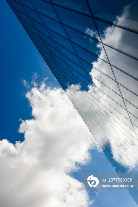 Clouds in a blue sky reflected against a glass wall